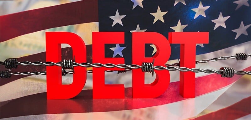 Red block letters spelling 'DEBT' are crossed by barbed wire against the background of the American flag.