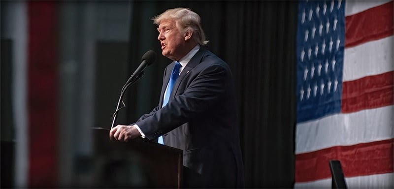 President Donald Trump delivers a high-profile national address before lawmakers, speaking at a podium against a large American flag backdrop while outlining his economic agenda and tariff strategy.